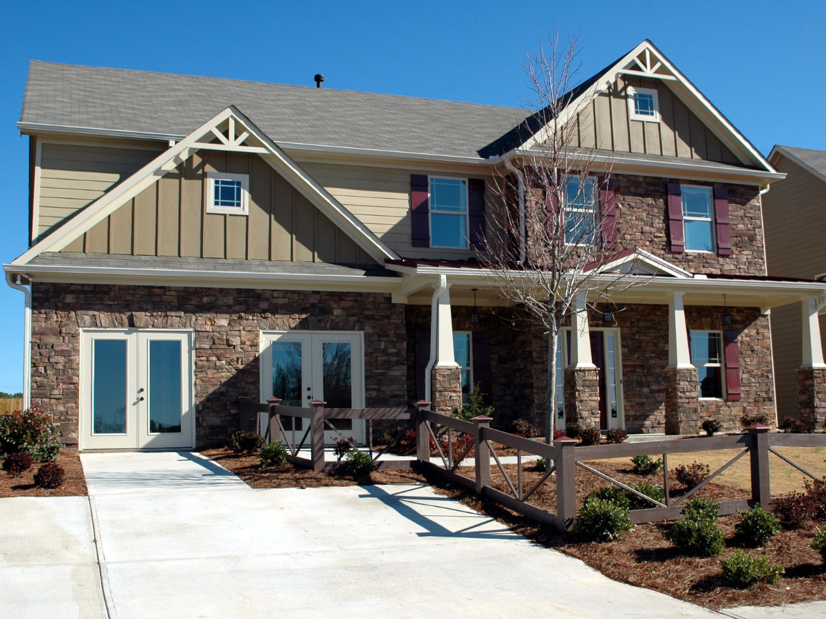 Two story craftsman home with stone front and dark shingle roof